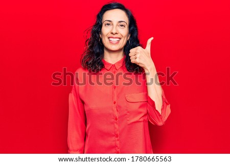 Young beautiful hispanic woman wearing casual clothes smiling happy and positive, thumb up doing excellent and approval sign 
