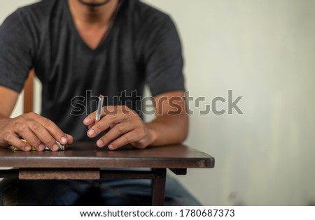 man sit in the table and holds cigarette for smoking. concept for cancer, illness, crime. 