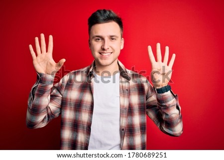Young handsome caucasian man wearing casual modern shirt over red isolated background showing and pointing up with fingers number nine while smiling confident and happy.