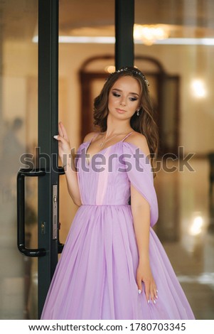 Young woman in beautiful purple dress posing to photographer by the restaurant