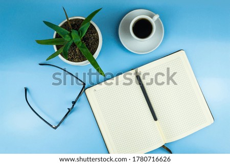 Workspace of a creative office worker. Working with a cup of coffee, using a phone, notepad, pen and glasses