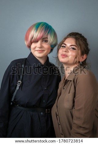 Two pretty young white girls smiling and posing on grey background people portrait with positive emotions