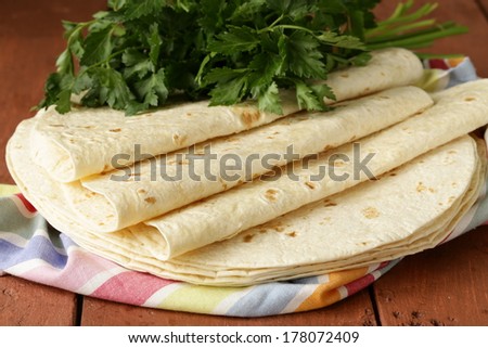 stack of homemade whole wheat flour tortillas on a wooden table
