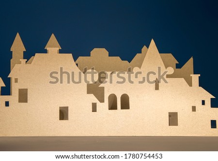 A street of houses in two rows, cut out of cardboard, imitating a small European city on a dark blue background