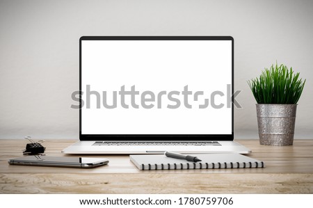 Laptop with blank screen on beige wooden table in office with phone, paper clip, flower grass and notebook - 3d illustration