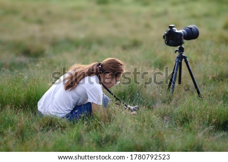 asian woman photographer holding camera in the green grass field