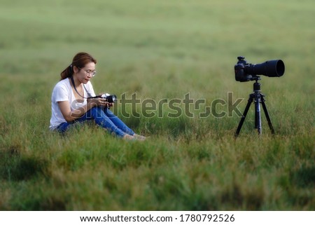 asian woman photographer holding camera in the green grass field