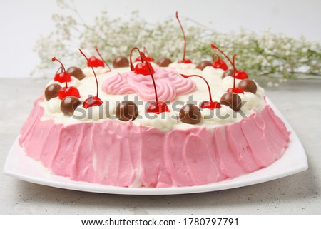 Biscuit Cake with Cream Cheese White And Pink Colors Decorated With Cherry And Chocolate Balls On White Plate. Side View. 