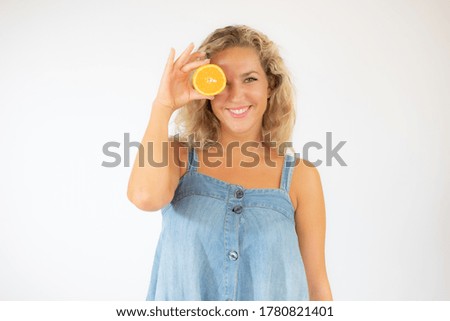Pretty blonde woman in blue dress smiling with an orange in the eye