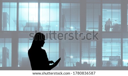 Silhouette of Asian business woman using tablet on office building background, concept of technology or communication.Several silhouettes of businesspeople interacting  background business centrer