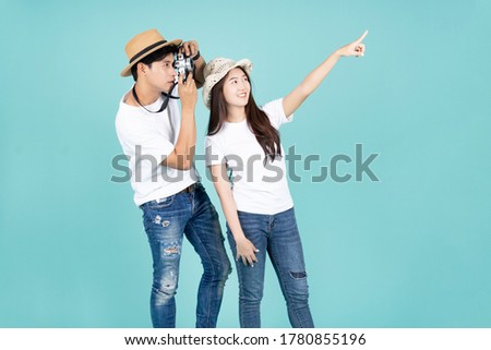 attractive asian couple traveler exciting with take photo camera action and point finger to copy space with green mint color background