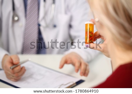 Cropped head of male physician recommending pills in orange bottle to woman who is holding remedy Royalty-Free Stock Photo #1780864910