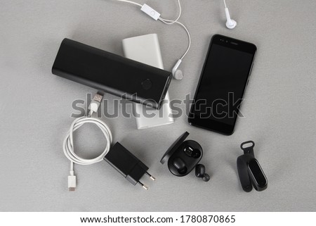 Mobile accessories include white and black power bank, wireless headphone adapter and smartwatch and type C cable Royalty-Free Stock Photo #1780870865