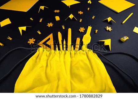 A concept on the subject back to school. The student's yellow stationery on a black background.