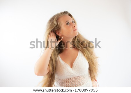 Pretty blonde girl in a white dress making the listening gesture