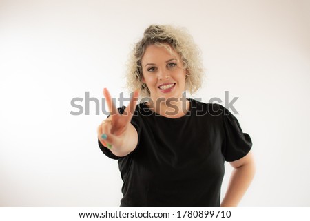 Blonde young woman smiling making victory gesture