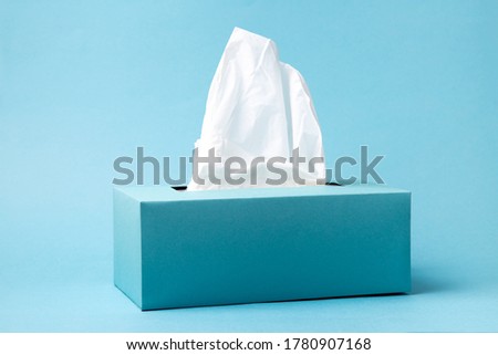 Light blue tissue box on blue background. Cold and flu concept. Minimal monochromatic composition. Royalty-Free Stock Photo #1780907168