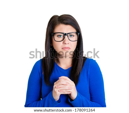 Closeup portrait of nervous, young, beautiful woman with black glasses, anxiously holding her hands tightly to chest, craving for something, scared, afraid looking at you, isolated on white background