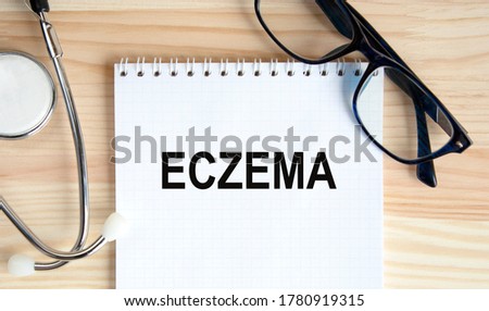 On a wooden table a notebook with the inscription of eczema, next to glasses and a stethoscope. medical concept.