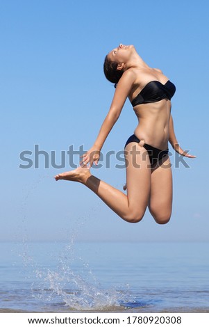 young Woman in bikini jumping on beach
