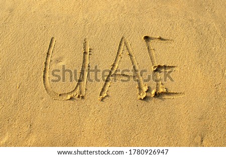 UAE word abbreviation on beach sand. UAE capital letters are written on a sand. Handwriting