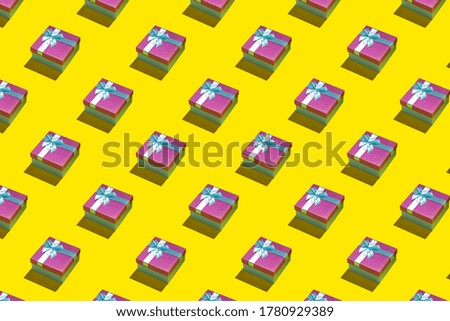 Colorful purple gift boxes with ribbons on bright yellow background. Abstract gift box pattern
