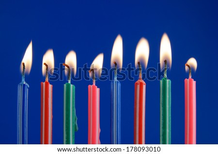 Burning colorful candles on blue background 