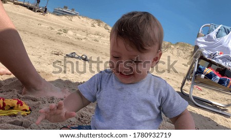 
Happy ecstatic baby boy infant at beach playing with sand