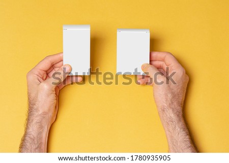 A man hands holding two pillboxes in front of yellow background, editable mock-up series ready for your design, selection path included.