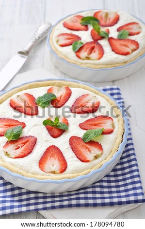Strawberry tart with ricotta filling in baking dish on wooden background