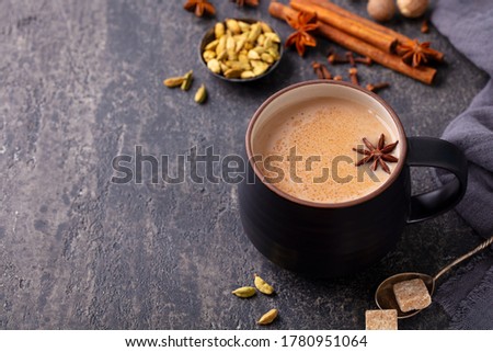 Indian masala tea with milk and spices in mug. Grey background. Close up. Copy space.