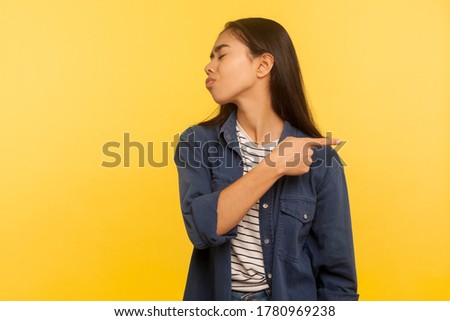 Get out, leave me! Portrait of annoyed vexed girl in denim shirt pointing way out and turning away with disrespect disgust, expressing resentment. indoor studio shot isolated on yellow background Royalty-Free Stock Photo #1780969238