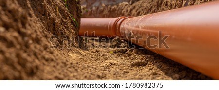 Plastic pipes in the ground during the construction of a building, bunner with copy space Royalty-Free Stock Photo #1780982375