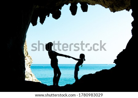mother and daughter play inside a cave by the sea