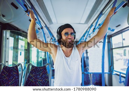 Portrait of an urban smiling man on a bus listening to music on headphones