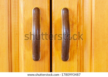 furniture handles on yellow wooden cabinet doors. Close up view.