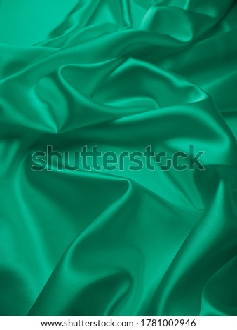 Beautiful elegant wavy emerald green satin silk luxury cloth fabric texture, abstract background design. Card or banner.