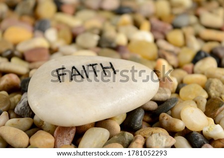 A smooth river stone is etched with the word faith for spiritual affirmation purposes. Royalty-Free Stock Photo #1781052293