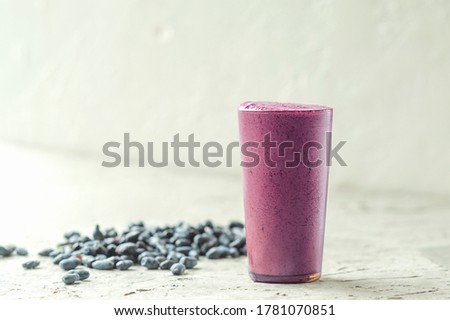 healthy vegetarian food, purple smoothies in a long glass mug on a light background and scattered berries Royalty-Free Stock Photo #1781070851