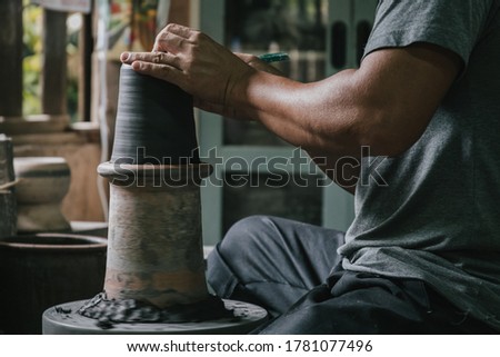 Asian professional artisan potter making art pot or vase handicraft on wheel in pottery workshop studio. Royalty-Free Stock Photo #1781077496