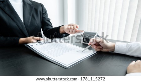 Real estate agent broker hand over the house key to the new owner after completing the signing according to agreement renting a house and buy house insurance Home insurance concept.