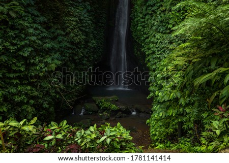 Waterfall landscape. Beautiful hidden Leke Leke waterfall in Bali. Tropical scenery. Waterfall in tropical rainforest. Slow shutter speed, motion photography. Horizontal layout.