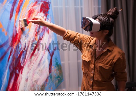 Creative painter with vr headset painting on canvas in art studio. Modern artwork paint on canvas, creative, contemporary and successful fine art artist drawing masterpiece