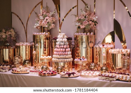 Luxury candy bar on golden wedding. Candy bar decorated by flowers standing of festive table with deserts, and cakes, strawberry tartlet, cupcakes and macarons. Wedding. Reception Tartlets Royalty-Free Stock Photo #1781184404