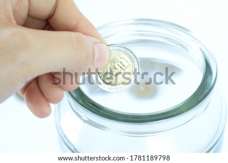 Close up women hands put coin in jar. Saving money growing business concept.

