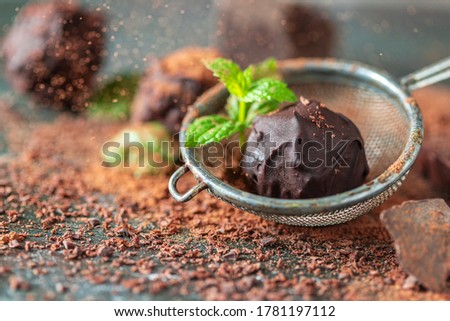 Delicious chocolate truffles with mint, cocoa powder and dark chocolate on a dark wooden background. Selective focus, copy space