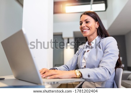 Young woman working from home, while in quarantine isolation during the Covid-19 health crisis. Portrait of a beautiful young business woman smiling and looking at laptop screen