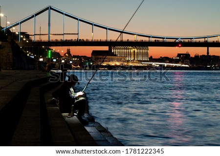 fishing at night. The old man is fishing after sunset in the city.