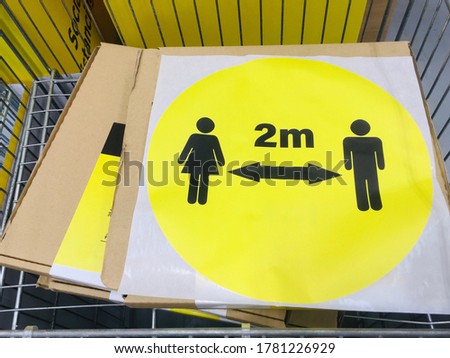 Yellow round sticker with symbol of one male, one female, two way arrow and text 2m in black concept of social distancing in shops during the easing of coronavirus pandemic outbreak in July 2020