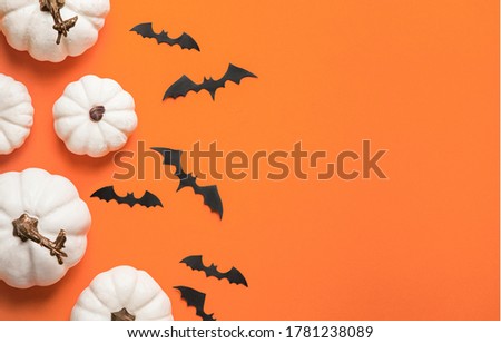 Happy Hallooween backgroung. Flat lay composition on orange paper. White pumpkins and bats.